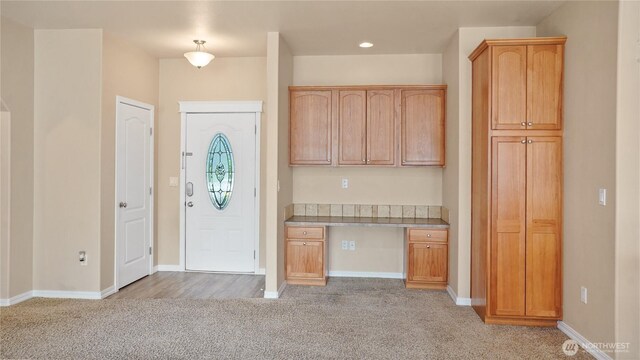 foyer featuring recessed lighting, baseboards, light colored carpet, and built in study area