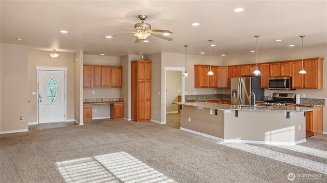 kitchen featuring a ceiling fan, stainless steel appliances, and light colored carpet