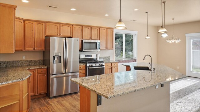 kitchen with light stone counters, appliances with stainless steel finishes, a sink, light wood-style floors, and visible vents