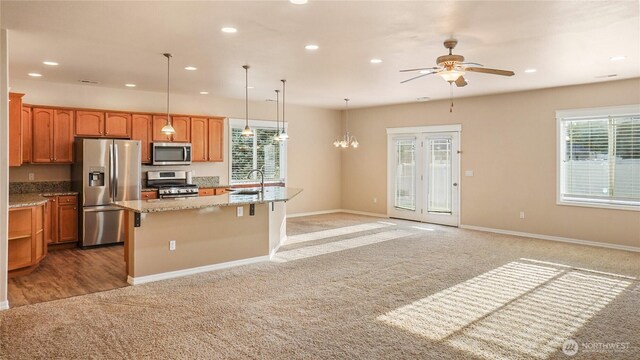 kitchen featuring stainless steel appliances, plenty of natural light, ceiling fan with notable chandelier, and light carpet