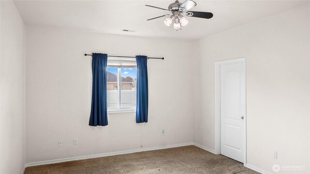 carpeted empty room with baseboards, a ceiling fan, and visible vents