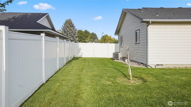 view of yard with central AC and a fenced backyard