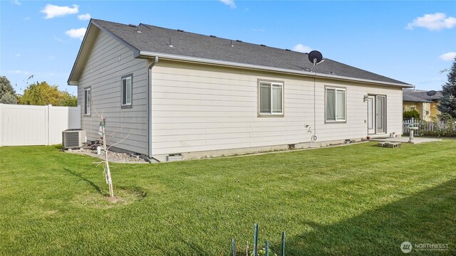 rear view of house with a yard, fence, and central AC unit