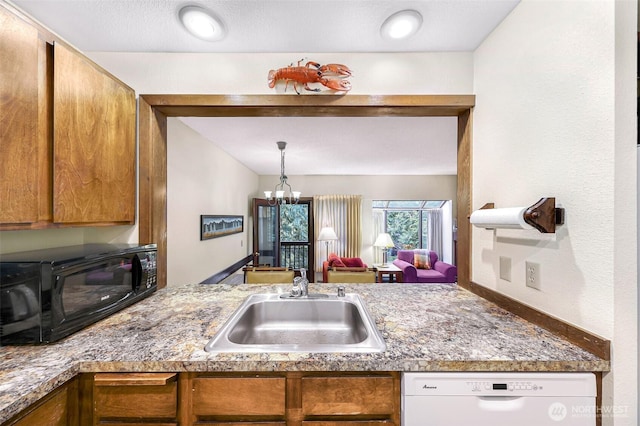 kitchen featuring a notable chandelier, black microwave, a sink, dishwasher, and brown cabinetry