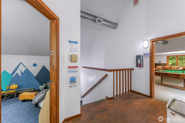 corridor featuring visible vents, baseboards, brick floor, and an upstairs landing
