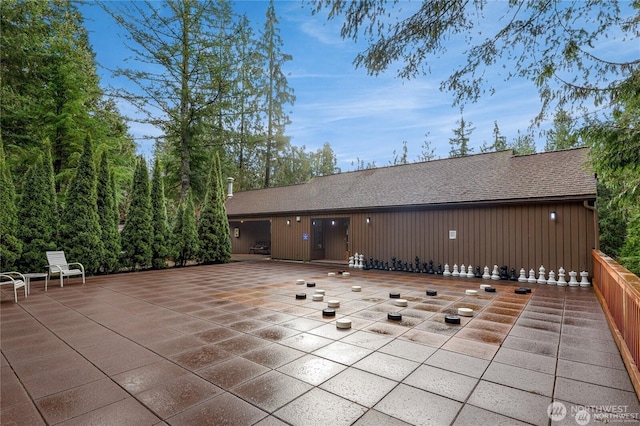 back of house featuring a patio and a shingled roof