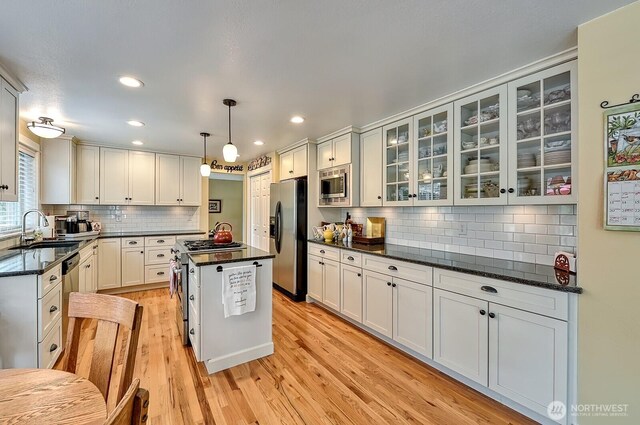 3506 S Grace Ln, Bellingham, WA 98226 - kitchen featuring tasteful backsplash, a sink, light wood finished floors, glass insert cabinets, and stainless steel appliances