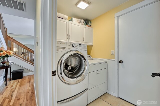 3506 S Grace Ln, Bellingham, WA 98226 - clothes washing area with visible vents, cabinet space, washing machine and dryer, and light wood-style floors