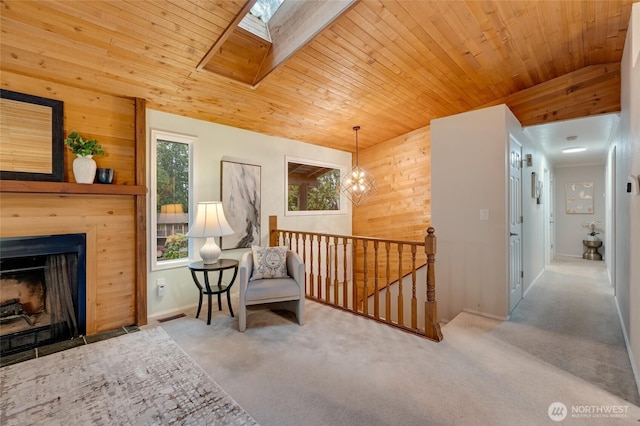 sitting room featuring carpet flooring, wood walls, plenty of natural light, an upstairs landing, and visible vents