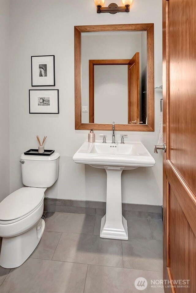 bathroom with tile patterned flooring, baseboards, and toilet