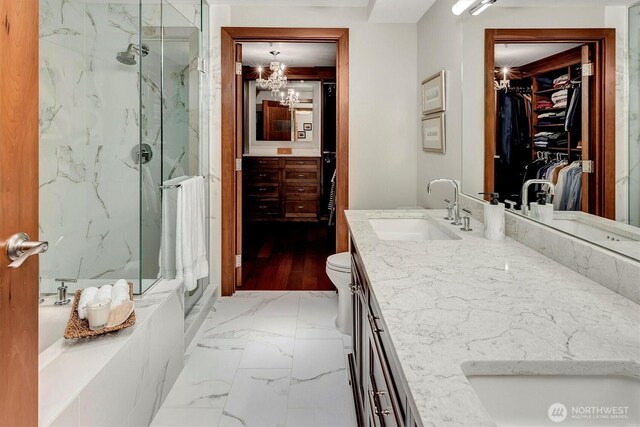 full bathroom featuring a walk in closet, vanity, marble finish floor, a notable chandelier, and a marble finish shower