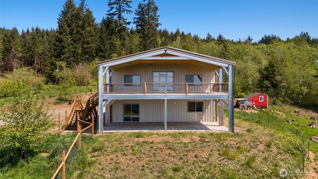 rear view of property with a patio area, stairs, a forest view, a deck, and a yard