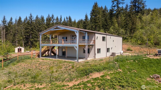rear view of house featuring stairs, a deck, a patio, and a wooded view