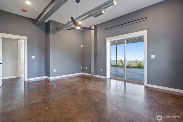 spare room with finished concrete floors, baseboards, ceiling fan, and a high ceiling