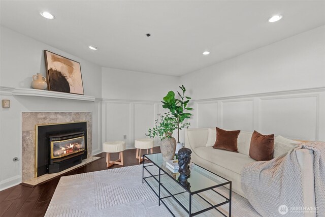 living area featuring a tiled fireplace, a decorative wall, recessed lighting, and wood finished floors