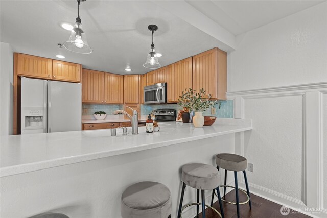 kitchen featuring light countertops, dark wood finished floors, appliances with stainless steel finishes, backsplash, and decorative light fixtures