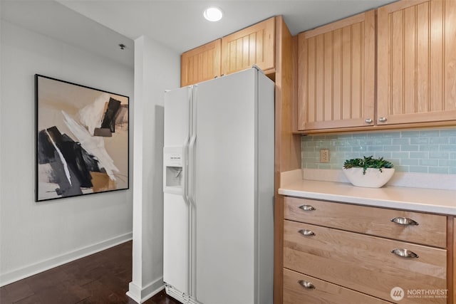 kitchen featuring light brown cabinetry, tasteful backsplash, white refrigerator with ice dispenser, and baseboards