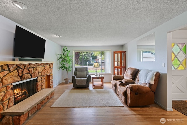 living area with baseboards, a fireplace, a textured ceiling, and wood finished floors