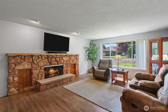 living area with a textured ceiling, wood finished floors, and a fireplace