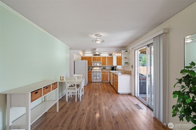 kitchen featuring open shelves, crown molding, light wood-style floors, and white appliances