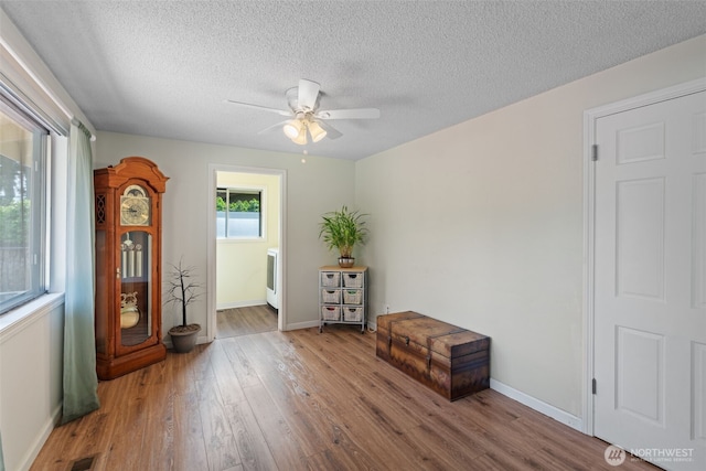 empty room with baseboards, ceiling fan, a textured ceiling, and wood finished floors
