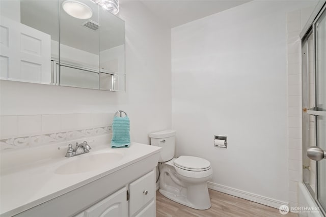 bathroom featuring toilet, wood finished floors, visible vents, baseboards, and vanity