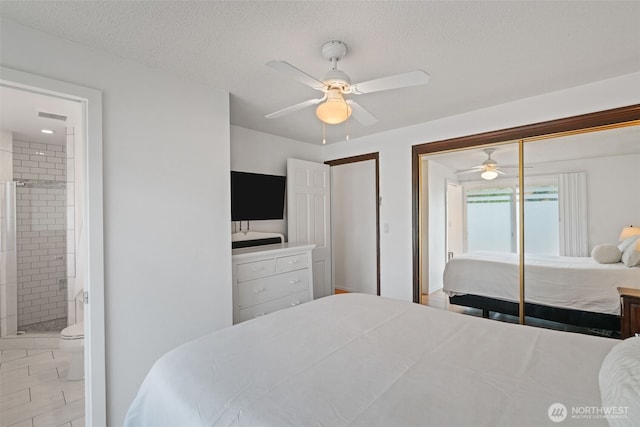 bedroom with a closet, a textured ceiling, ensuite bath, visible vents, and ceiling fan