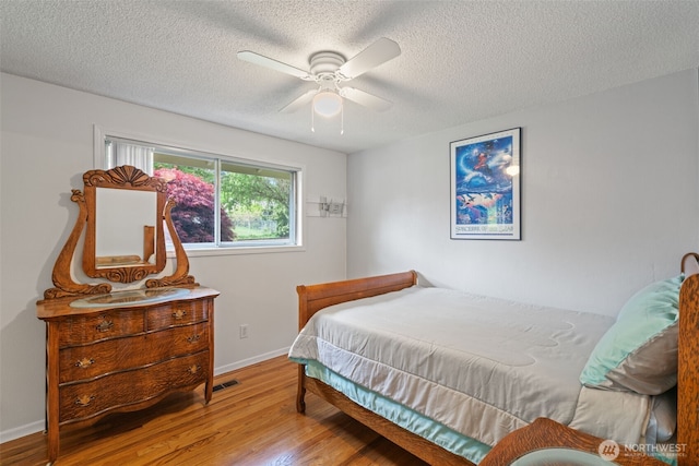 bedroom featuring baseboards, a ceiling fan, a textured ceiling, and wood finished floors