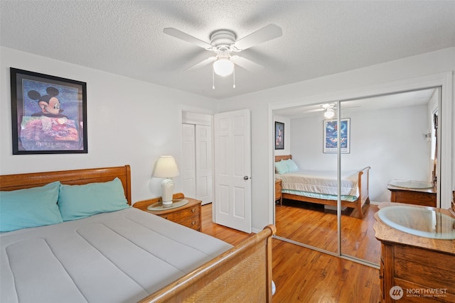 bedroom with wood finished floors, a sink, a closet, a textured ceiling, and ceiling fan