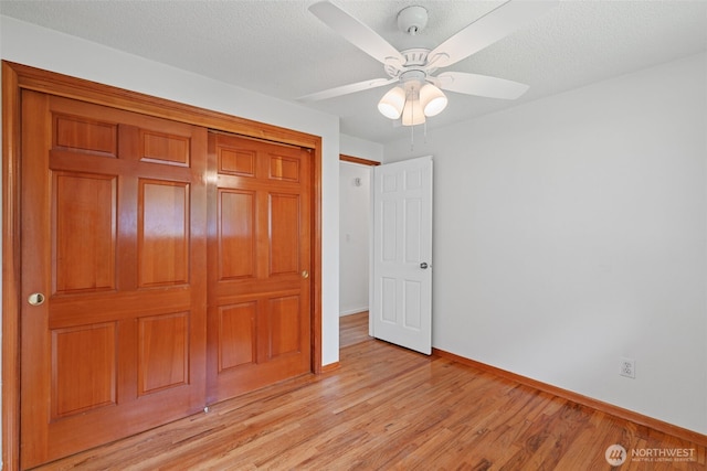 unfurnished bedroom with ceiling fan, baseboards, a closet, and light wood-style floors