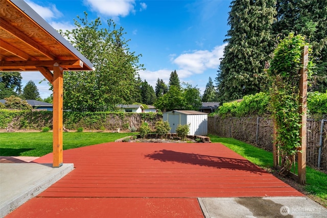 deck with an outdoor structure, a lawn, a fenced backyard, and a shed