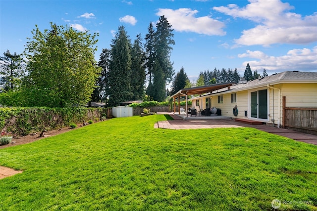 view of yard with a storage shed, an outdoor structure, a fenced backyard, and a patio