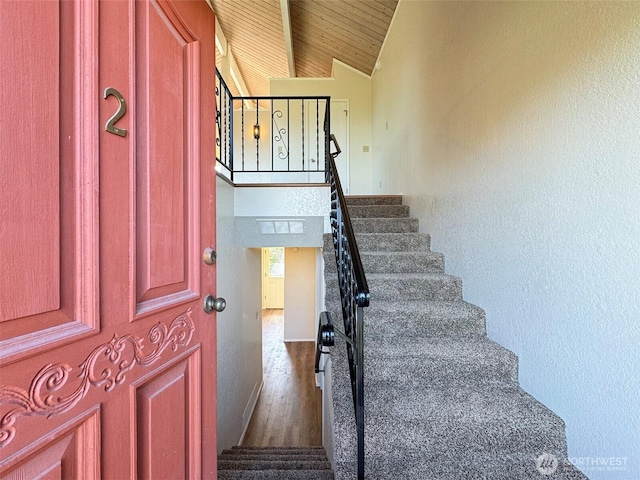 staircase with wood finished floors, lofted ceiling, and wooden ceiling