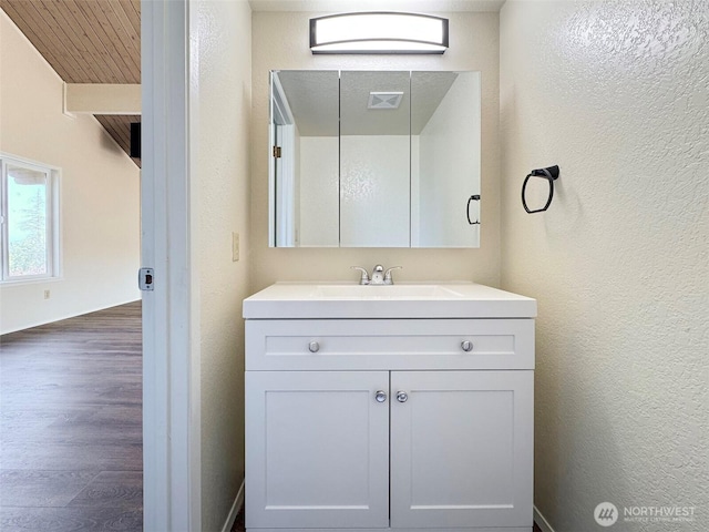 bathroom featuring a textured wall, visible vents, wood finished floors, and vanity