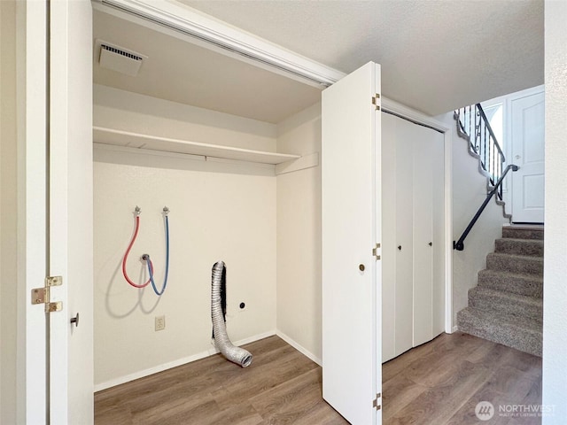 laundry room with baseboards, laundry area, wood finished floors, and visible vents