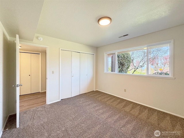 unfurnished bedroom with visible vents, carpet flooring, baseboards, and a closet