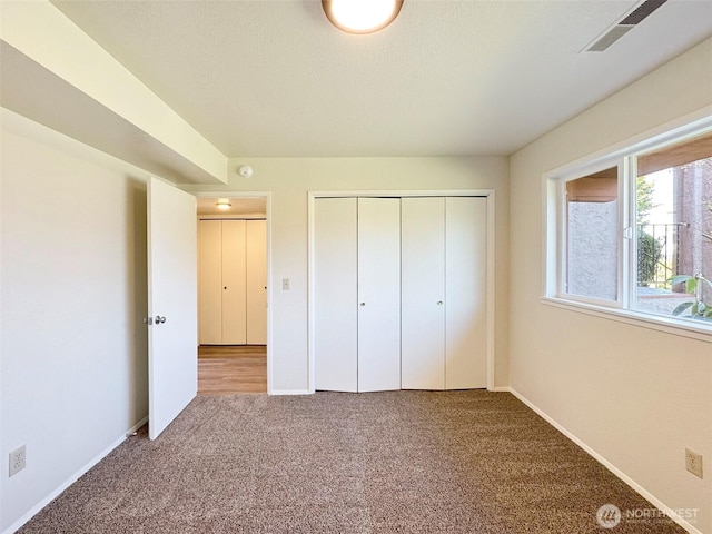 unfurnished bedroom with carpet floors, baseboards, visible vents, and a closet