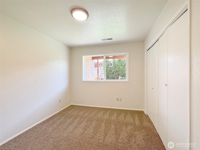 unfurnished bedroom with carpet floors, baseboards, visible vents, and a closet