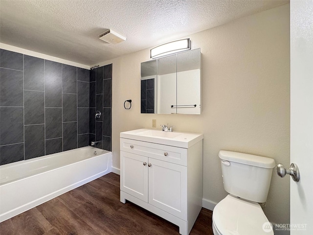 bathroom featuring vanity, wood finished floors, toilet, a textured ceiling, and  shower combination