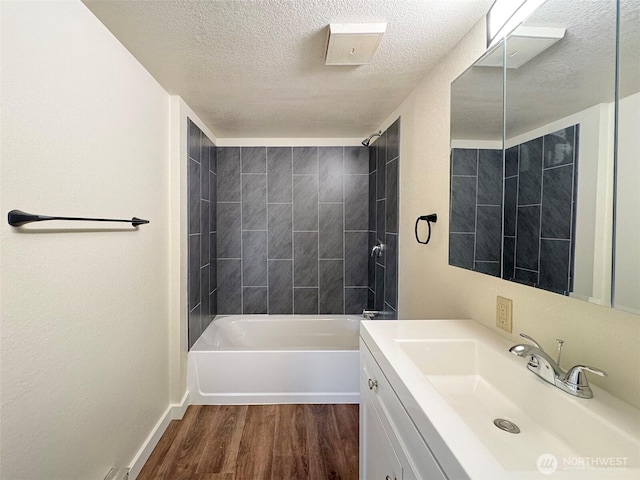 bathroom featuring vanity, a textured ceiling, baseboards, wood finished floors, and shower / bathing tub combination