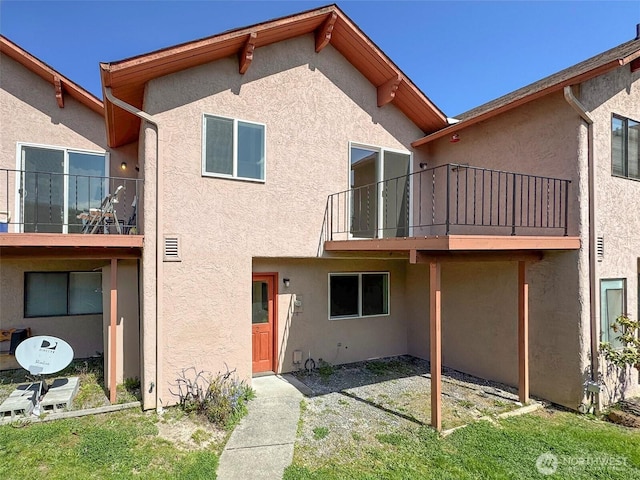 rear view of property featuring a balcony and stucco siding
