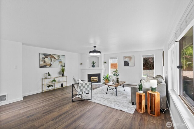 living room with dark wood-style floors, a glass covered fireplace, and baseboards