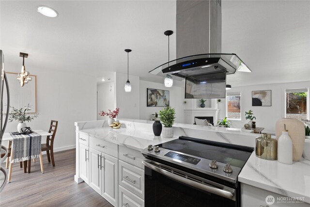 kitchen with stainless steel range with electric stovetop, light stone countertops, wood finished floors, a fireplace, and pendant lighting