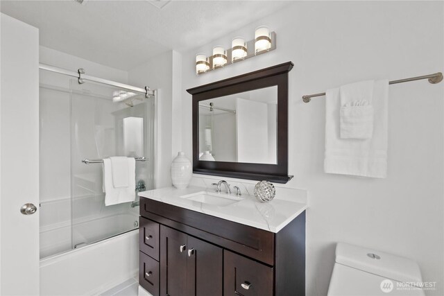 full bathroom featuring toilet, bath / shower combo with glass door, and vanity