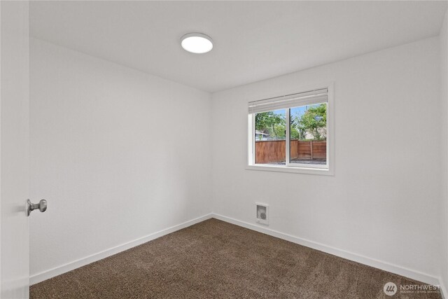 unfurnished room featuring dark colored carpet and baseboards
