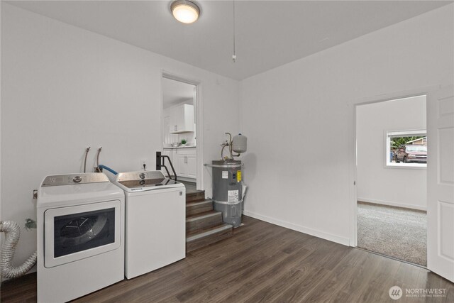 clothes washing area with washing machine and clothes dryer, dark wood finished floors, electric water heater, and baseboards