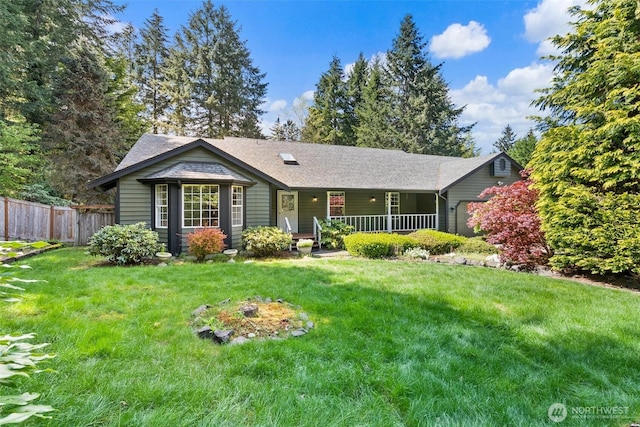 view of front of home featuring fence, covered porch, roof with shingles, and a front yard