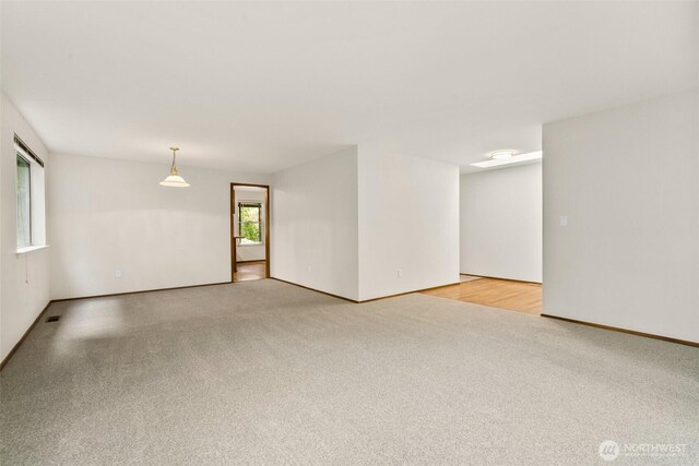 unfurnished room with baseboards and light carpet