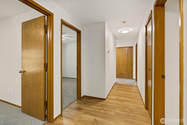 corridor featuring baseboards and light wood-type flooring