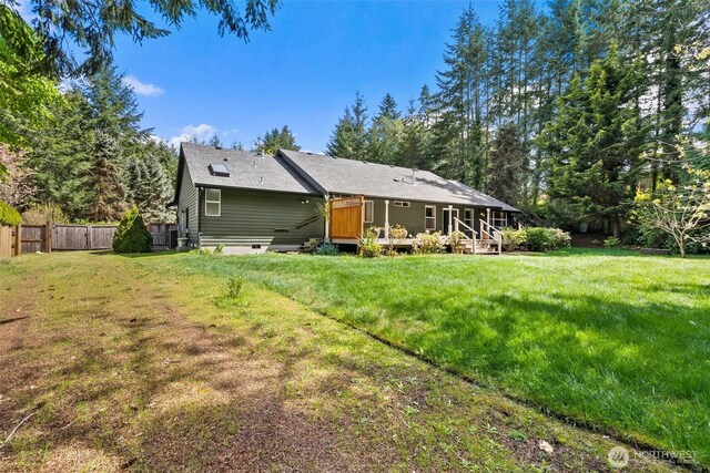 rear view of house featuring a lawn, fence, and a wooden deck